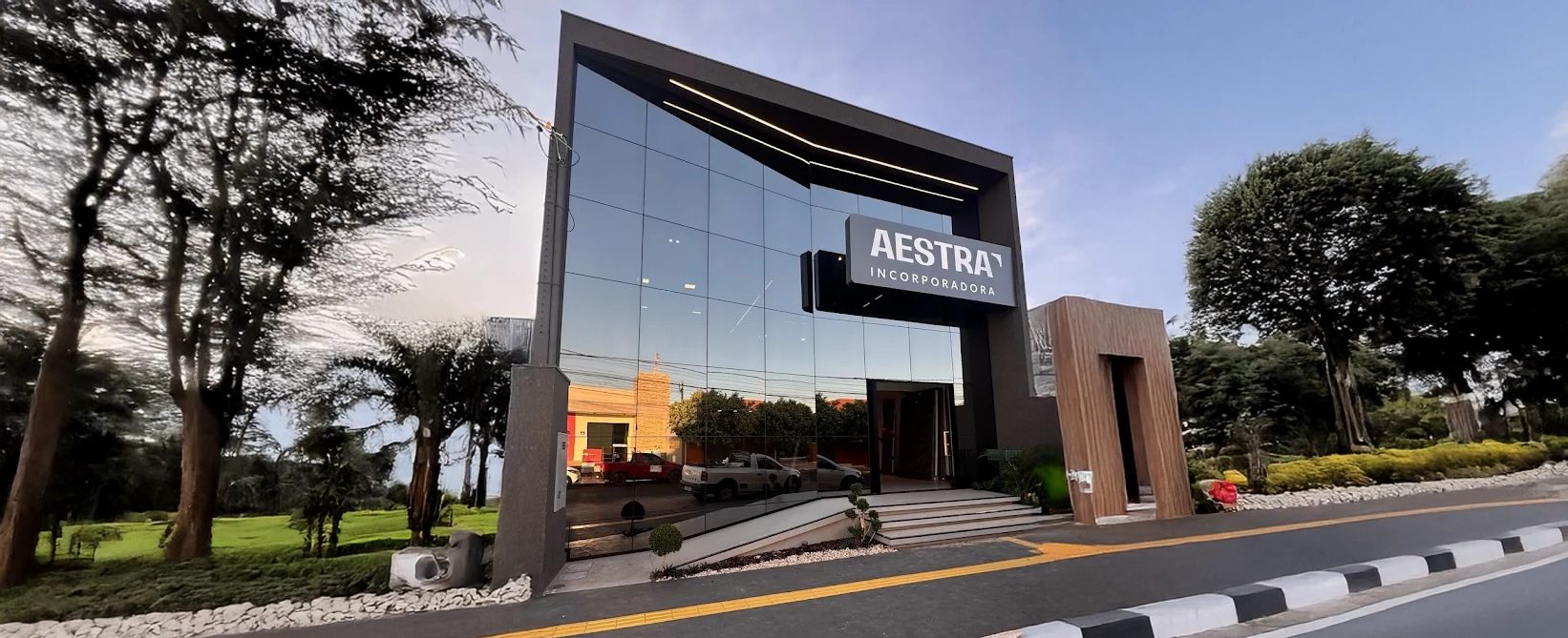 Fachada envidraçada da central de vendas da Aestra ao entardecer